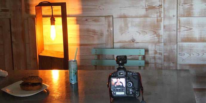 Macchina fotografica e hamburger su tavolo durante pausa shooting fotografico